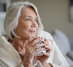 Woman smiling while drinking tea at home