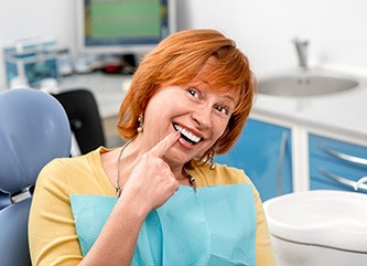 An older woman pointing out her new dental implant