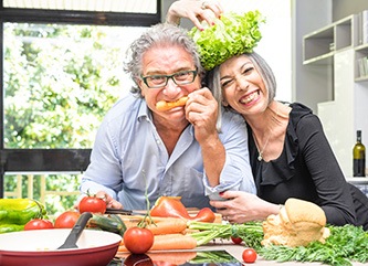 A senior couple having fun in the kitchen with healthy foods