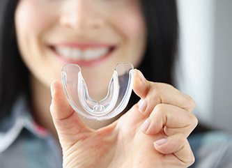 A woman holding up a transparent mouth guard