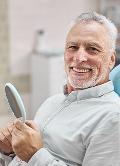 Patient smiling while holding dental mirror