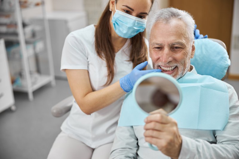 An older man admiring his successful dental implants
